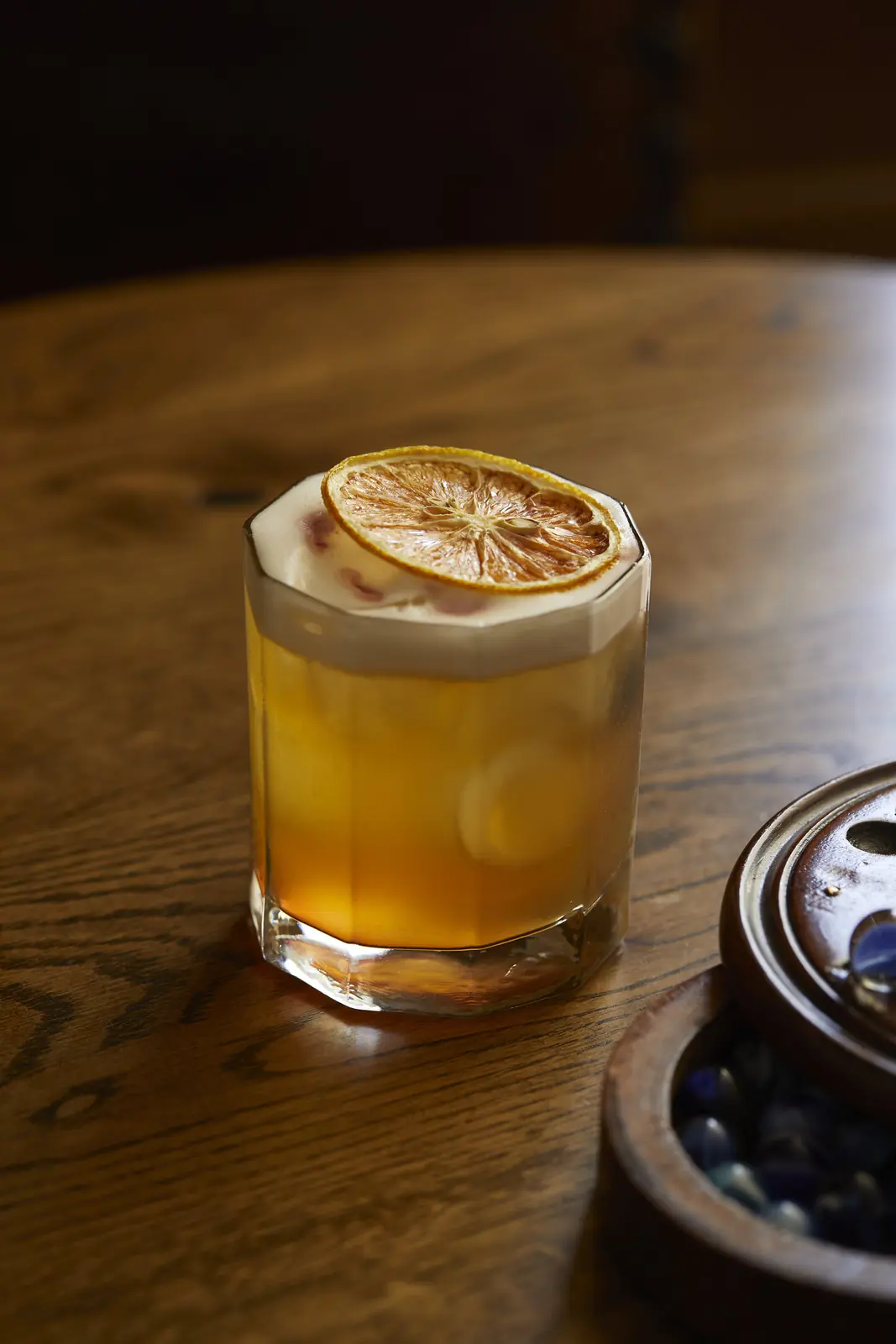 A whisky sour with a dried orange wheel